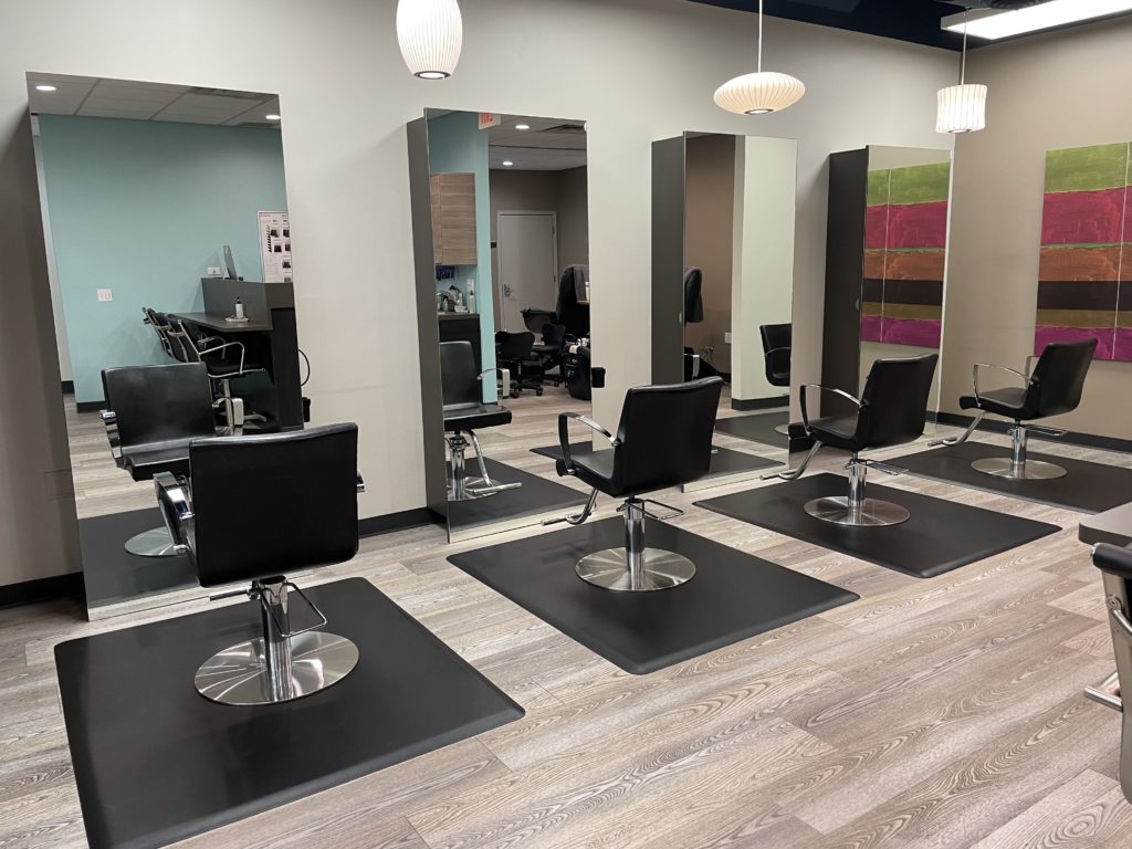 - Bella Salon in Madison, WI Modern hair salon interior with empty black styling chairs in front of large mirrors, light wooden floor, and colorful wall art—perfect for getting highlights or a fresh new hair color. - Bella Salon in Madison, WI